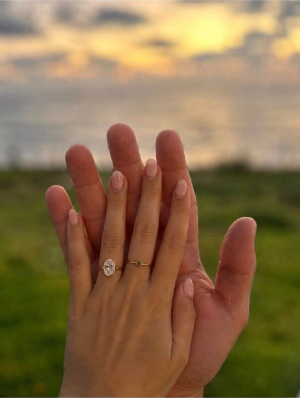 Oval diamond engagement ring on a hand at sunset